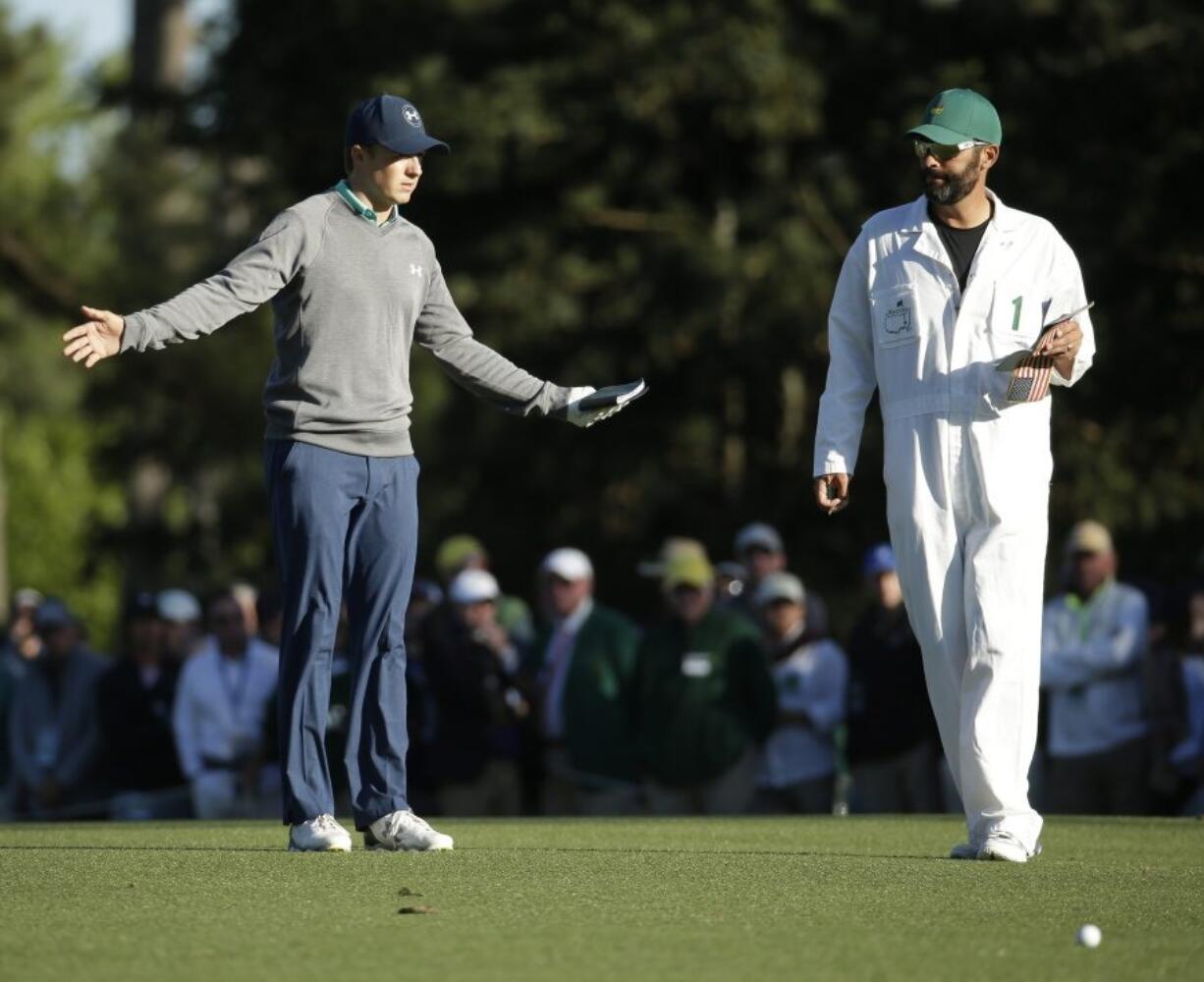 Jordan Spieth discusses his approach shot on the 15th hole with his caddie Michael Greller during the third round of the Masters golf tournament Saturday, April 9, 2016, in Augusta, Ga.