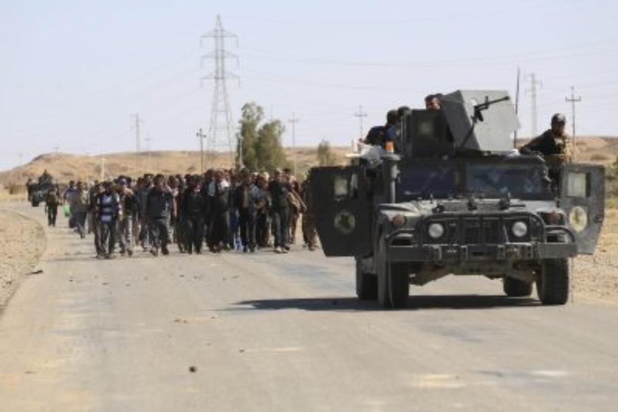 Iraqi counter terrorism forces escort people fleeing their homes Monday during clashes between Iraqi security forces and Islamic State militants in Hit, 85 miles west of Baghdad. Families, many with small children and elderly relatives, say they walked for hours Monday through desert littered with roadside bombs to escape.