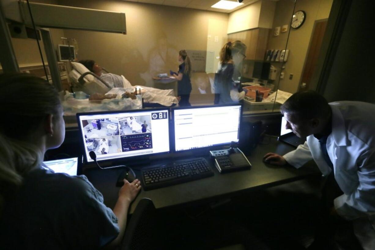 Clinical instructor Maureen Westfall, left, and simulation specialist coordinator Ben Oliver monitor a simulation room at the University of Michigan&#039;s nursing school where mannequins are used to teach students how to respond to real-life medical situations, including emergencies. The high-fidelity mannequins reside in six simulation rooms set up inside the Ann Arbor school&#039;s new Clinical Learning Center.