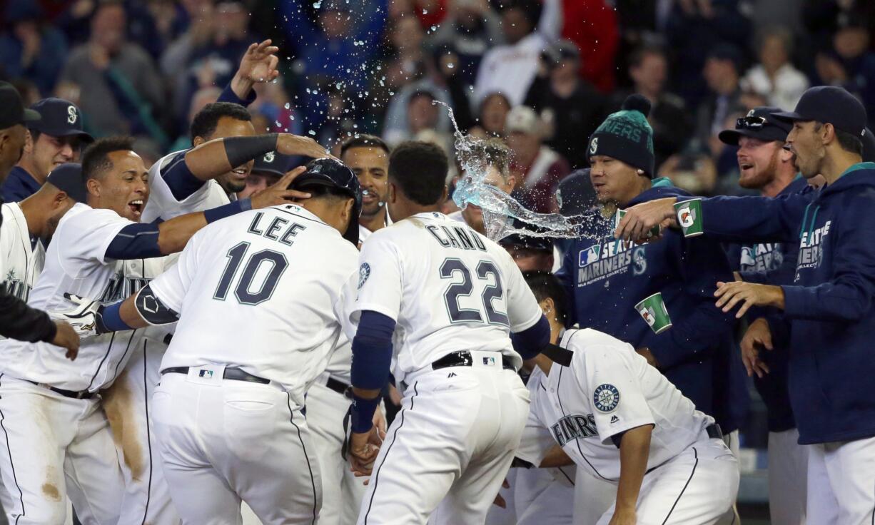 Seattle Mariners' Dae-Ho Lee (10) is greeted at the plate by teammates after he hit a walk-off two-run home run in the 10th inning of a baseball game against the Texas Rangers, Wednesday, April 13, 2016, in Seattle. The Mariners won 4-2. (AP Photo/Ted S.