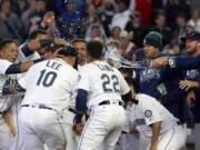 Seattle Mariners' Dae-Ho Lee (10) is greeted at the plate by teammates after he hit a walk-off two-run home run in the 10th inning of a baseball game against the Texas Rangers, Wednesday, April 13, 2016, in Seattle. The Mariners won 4-2. (AP Photo/Ted S.