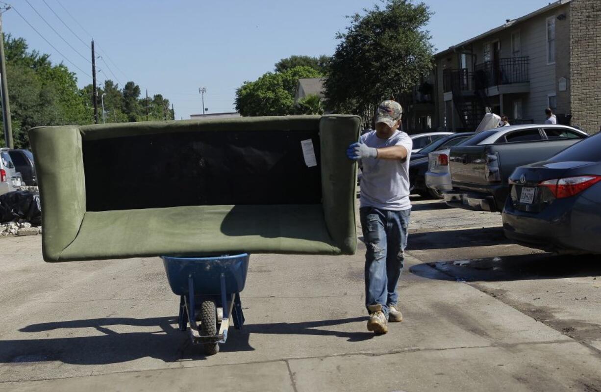 A flood-damaged couch is moved to the garbage by wheelbarrow Friday at the Rockbridge Springs Apartments in Houston.