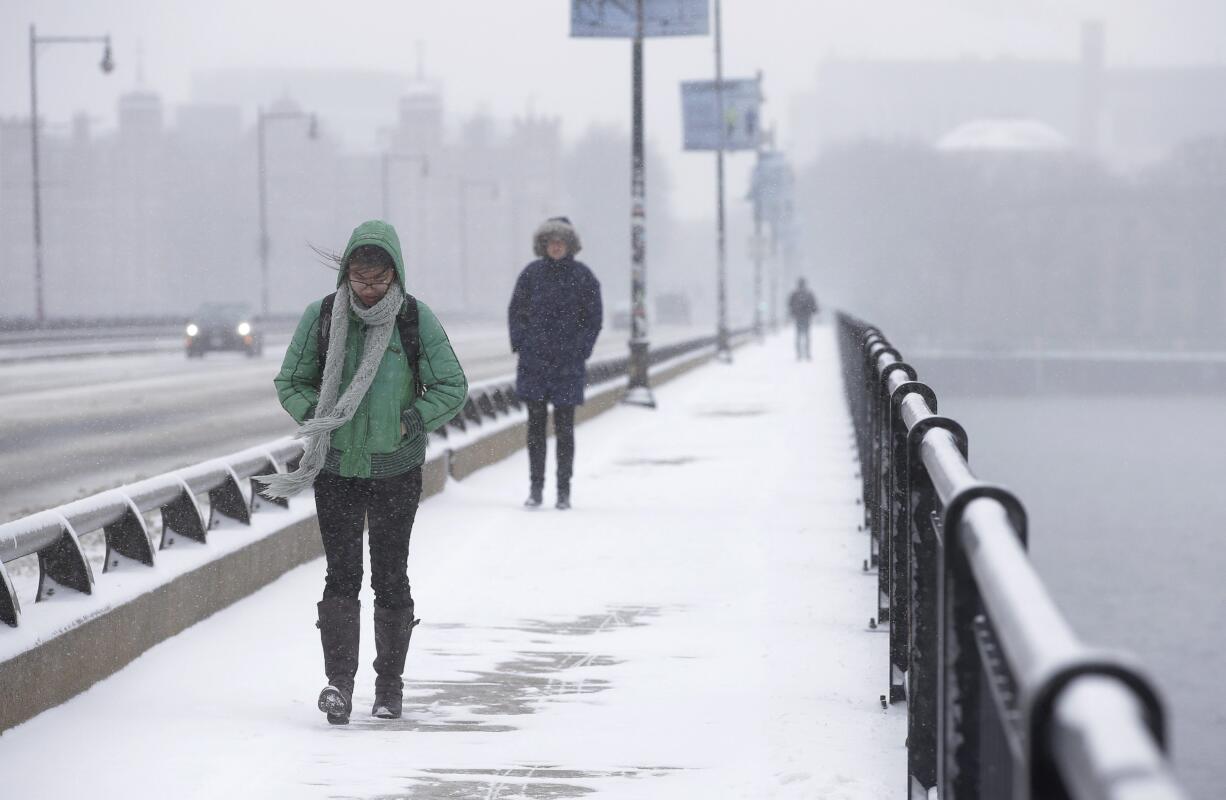 People on Monday make their way along a snow-covered bridge over the Charles River in Boston. An early spring cold front brought snow and gusty winds to the Northeast after the region had one of its mildest winters on record.