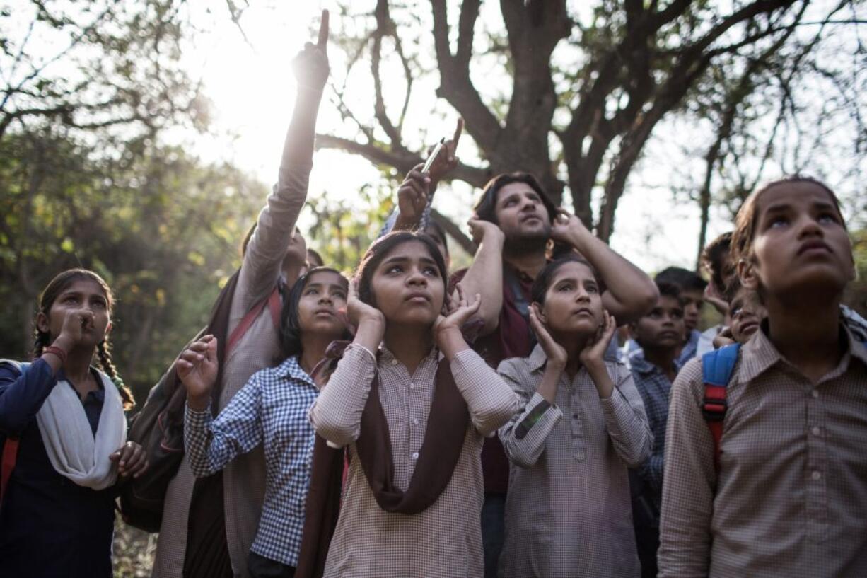 A group of students and a birder try to locate a bird by closely listening to its song April 2 during a school excursion through the vast Mangar Bani forest in Mangar, India.