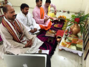 Priest Narayan Shastri, left, conducts a puja via Skype for the Shubhpuja company in Noida, India.