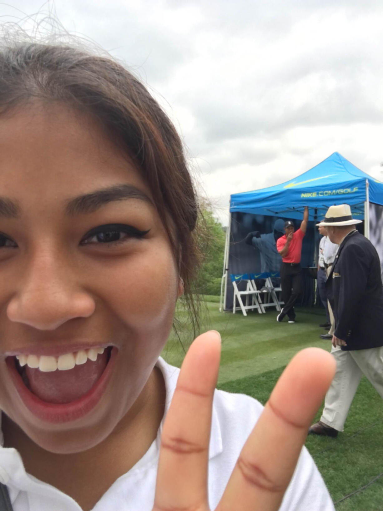 Julieta Rendon-Mendoza of Union High School poses for a selfie with Tiger Woods (in red) in the background at the Junior Invitational at Sage Valley Golf Course in South Carolina.