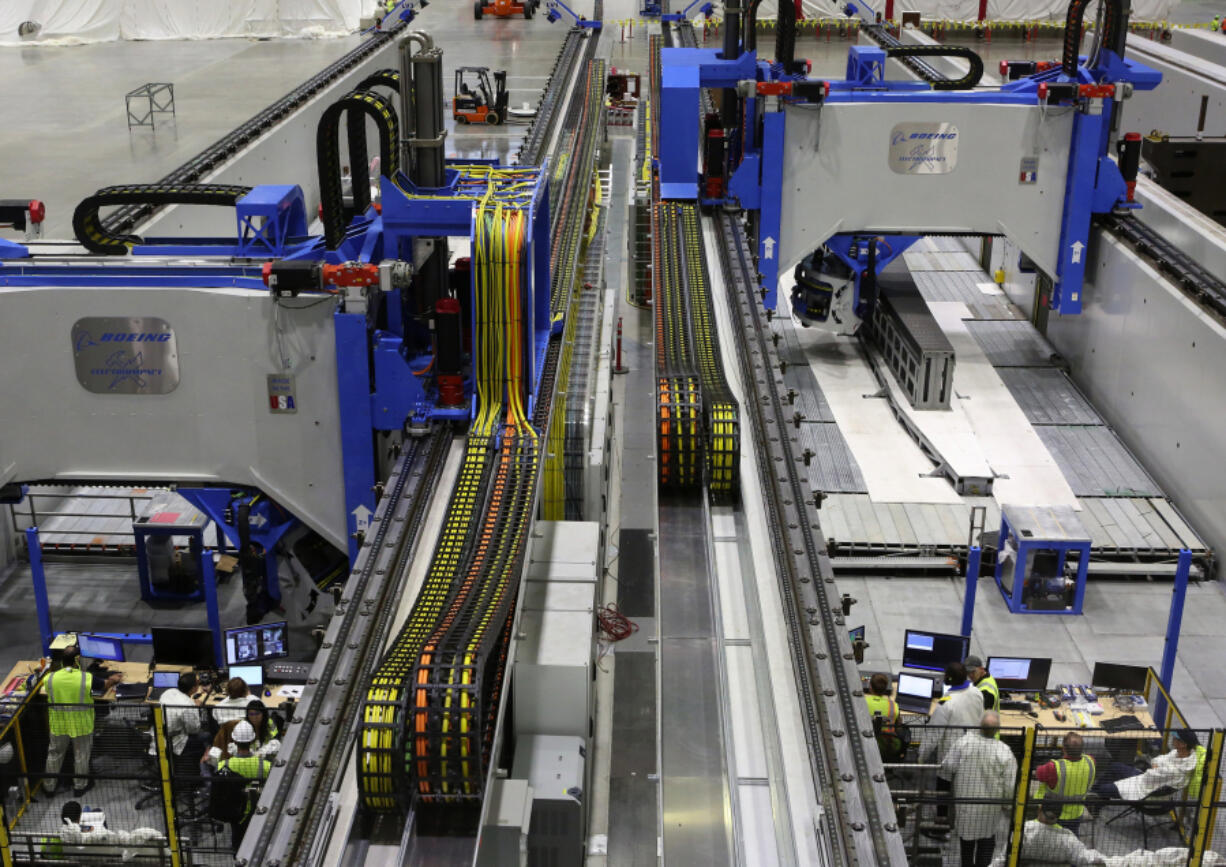 A crew tests a machine that makes a spar, seen at upper right, at Boeing&#039;s massive new 777X composite wing center, scheduled for its grand opening Friday in Everett.