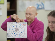 Seventh-grader Jasmine Erickson, 13, displays a diagram of titanium while working with fellow students including eighth-grader Mara Reese, also 13, right, at Lewis River Academy in Woodland.