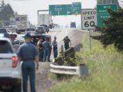 Officials gather along the southbound lane of Interstate 5 as they discuss how to remove a grenade from the side of the road Tuesday morning near Ridgefield.