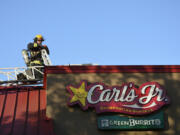 Vancouver firefighter Obie Bowman walks around the roof of a Carl&#039;s Jr. on Fourth Plain Boulevard on Monday evening following a fire there.