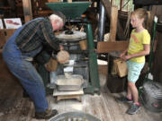 Fred Schulz, left, and volunteer Hadley Meldrum grind grain into flour and fill bags for visitors to take at the Cedar Creek Grist Mill&#039;s Bread and Butter Day on Saturday.