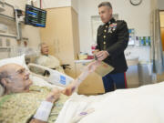 Ed Tice, left, a World War II Marine veteran, accepts a container of Iwo Jima beach sand Tuesday from Lt. Col. Brad Aiello at Legacy Salmon Creek Medical Center. Tice died Friday afternoon.