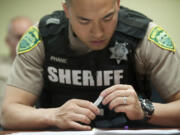 Clark County Sheriff&#039;s deputy Jack Phane inspects a dose of intranasal naloxone, the opioid overdose antidote, at a training session to learn how to administer the medication.