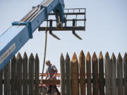 Matt Gembala helps get a replacement timber called a waler in place as Ausland Group workers renovate a section of the log palisade at the Fort Vancouver National Historic Site.