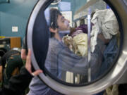 Joshua Matson, 28, stuffs clean clothes into a dryer at the Laundry Love laundromat in Vancouver. Laundry Love offers free laundry service on the second and fourth Thursday evenings of the month.