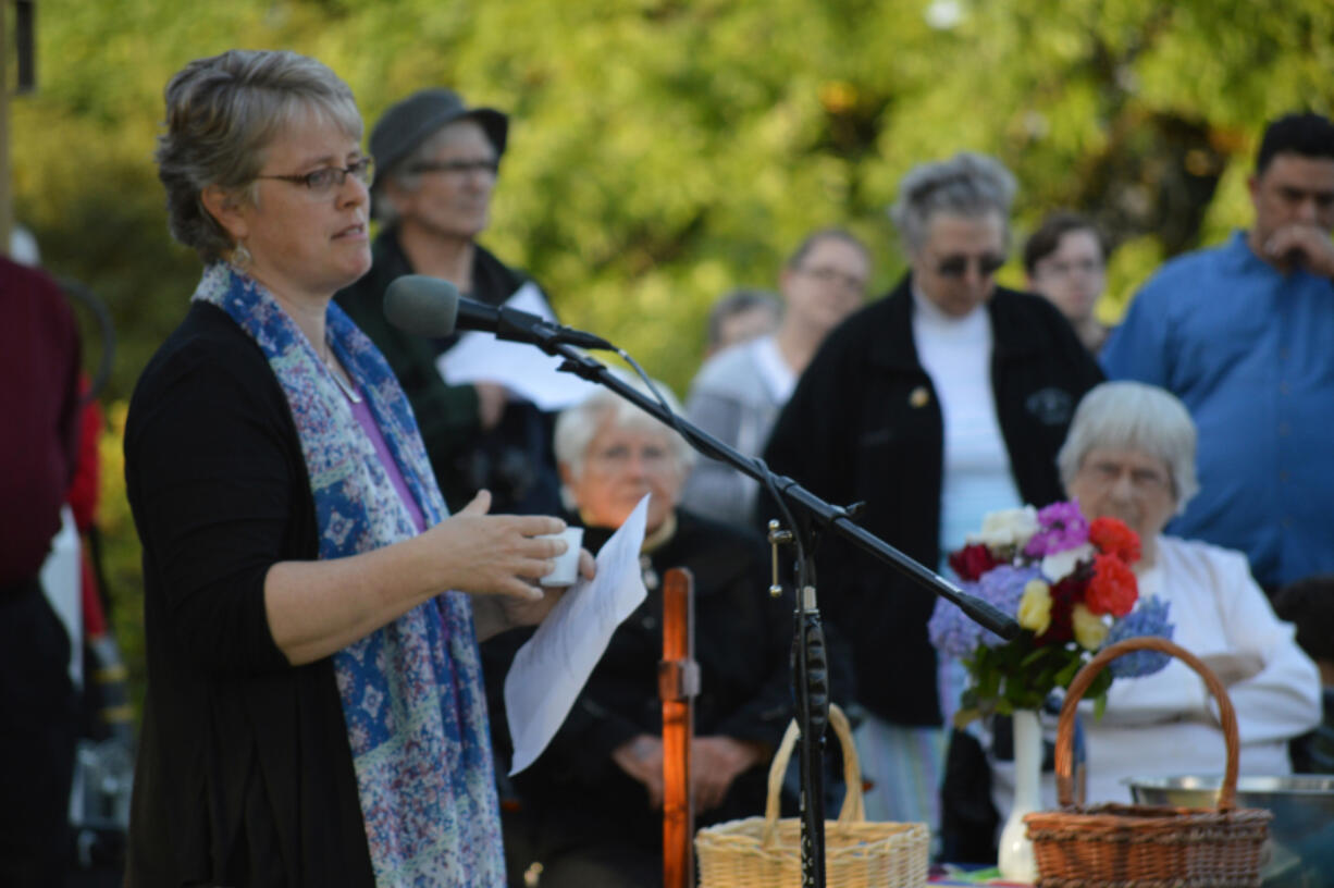 Pastor Jennifer Brownwell leads the congregation of the First Congregational United Church of Christ in prayer and song Wednesday evening as they gather in front of their church, which was damaged in a fire that morning.