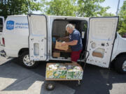 Stephen Burks, a driver for FISH of Vancouver, unloads boxes of donated food in front of Central Park Place.