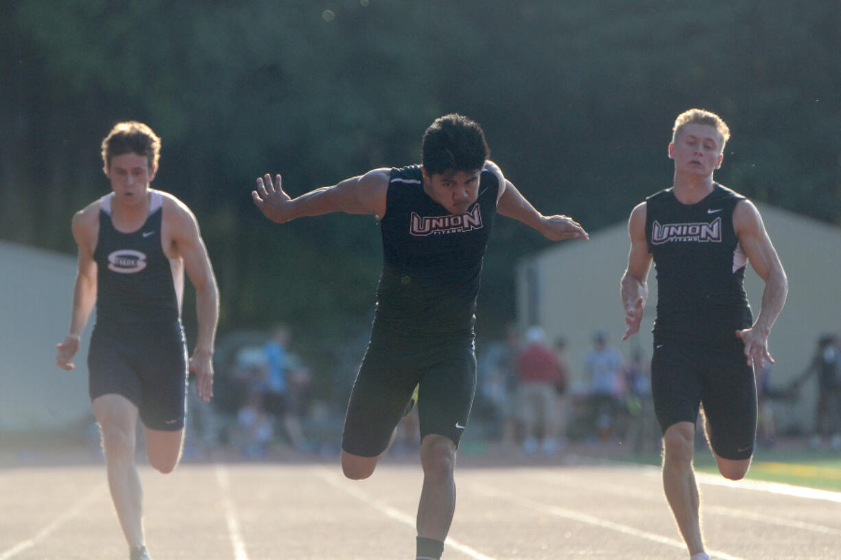 Union&#039;s Jilven Refil, center, breaks through the finish line to win the 100 meter race during the final day of the Greater St. Helens 4A district track meet at McKenzie Stadium.