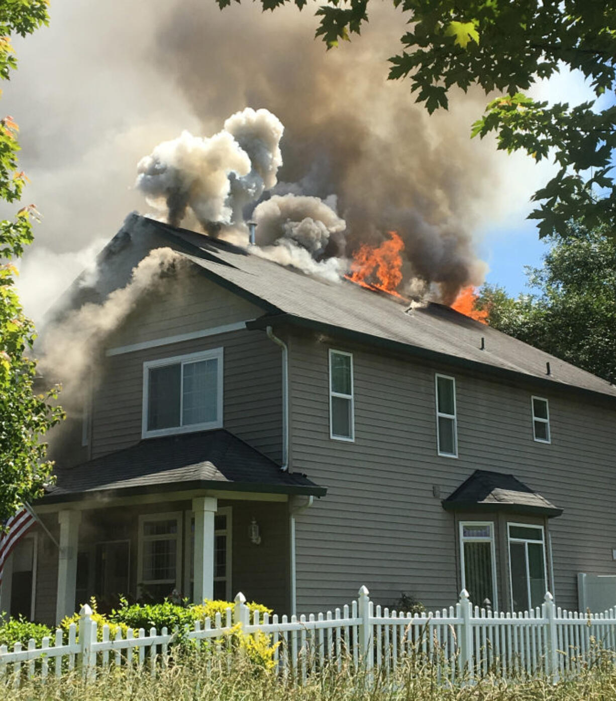 Flames are visible from the top of a house Monday afternoon in Battle Ground.