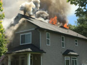 Flames are visible from the top of a house Monday afternoon in Battle Ground.