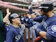 Seattle Mariners' Franklin Gutierrez, right, celebrates with Felix Hernandez, second from left, and teammates in the dugout after hitting a three-run home run off Cincinnati Reds starting pitcher John Lamb in the fourth inning of a baseball game, Saturday, May 21, 2016, in Cincinnati.