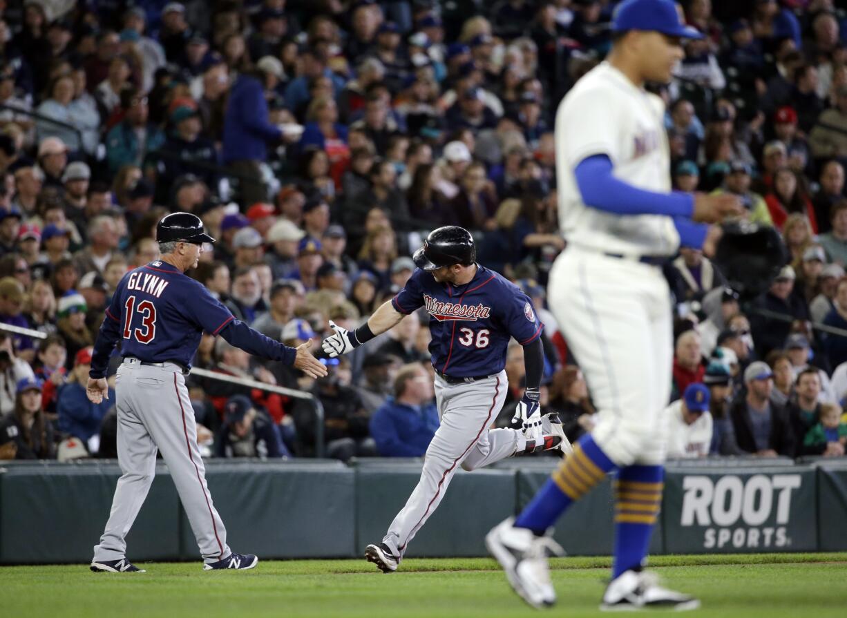 Seattle Mariners starting pitcher Taijuan Walker, right, returns to the mound as Minnesota Twins' Robbie Grossman (36) is congratulated by third base coach Gene Glynn on Grossman's home run in the second inning of a baseball game Sunday, May 29, 2016, in Seattle.