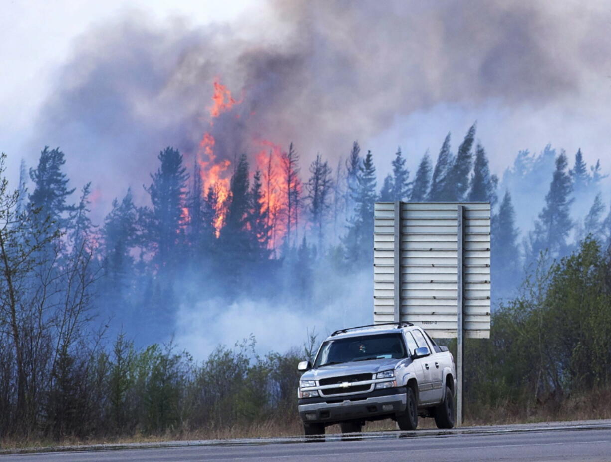 Flames flare up from hotspots Sunday along a highway to Fort McMurray, Canada.