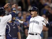 Seattle Mariners' Ketel Marte, right, is greeted by Leonys Martin as Marte crosses home on his three-run home run and Tampa Bay Rays catcher Hank Conger looks on in the sixth inning of a baseball game Monday, May 9, 2016, in Seattle.