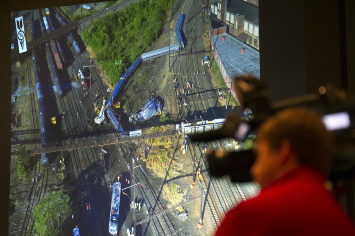 A photograph is displayed on a video monitor of the derailment of Amtrak passenger train in Philadelphia last year during a National Transportation Safety Board meeting on the derailment Tuesday in Washington.