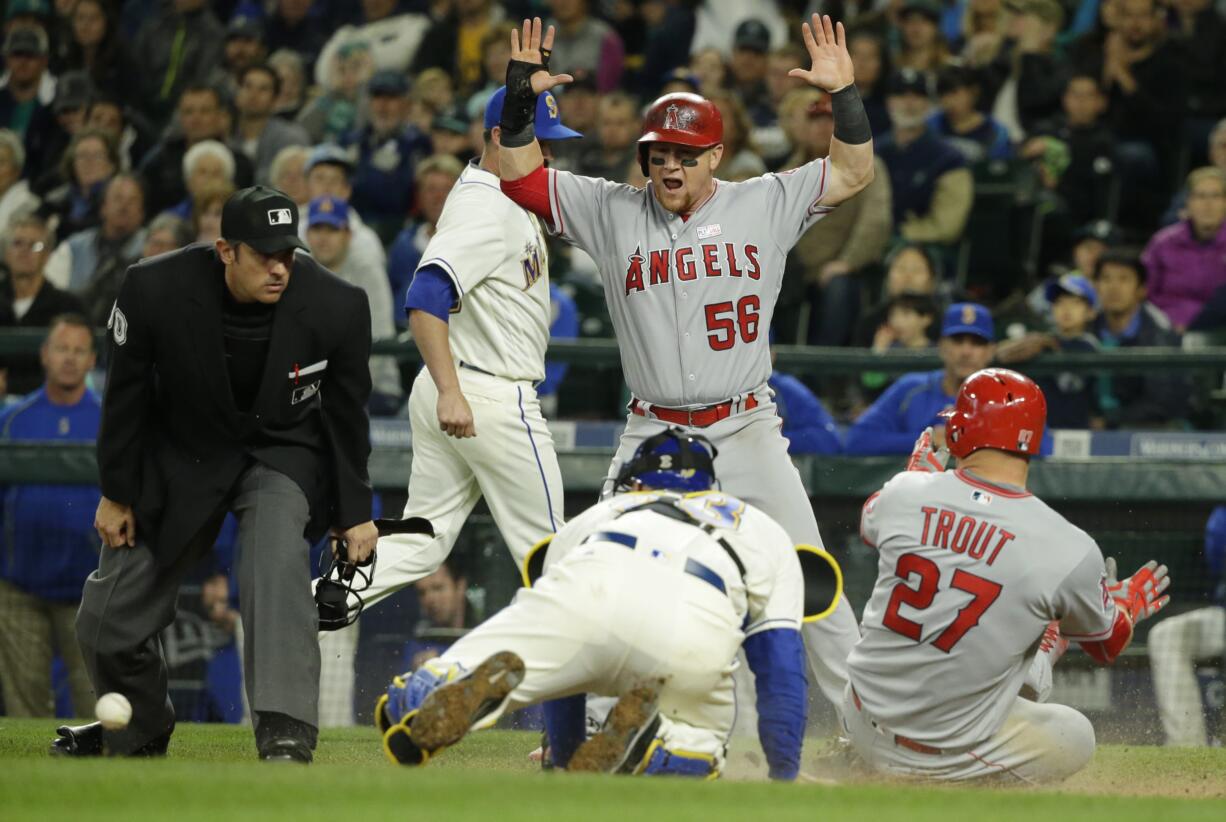 Los Angeles Angels' Mike Trout slides safely into home as Angels' Kole Calhoun (56) reacts to Seattle Mariners catcher Chris Iannetta bobbling the ball on the tag attempt in the eighth inning of a baseball game, Sunday, May 15, 2016, in Seattle. Trout and Calhoun scored on a two-run single hit by Angels' Daniel Nava. (AP Photo/Ted S.