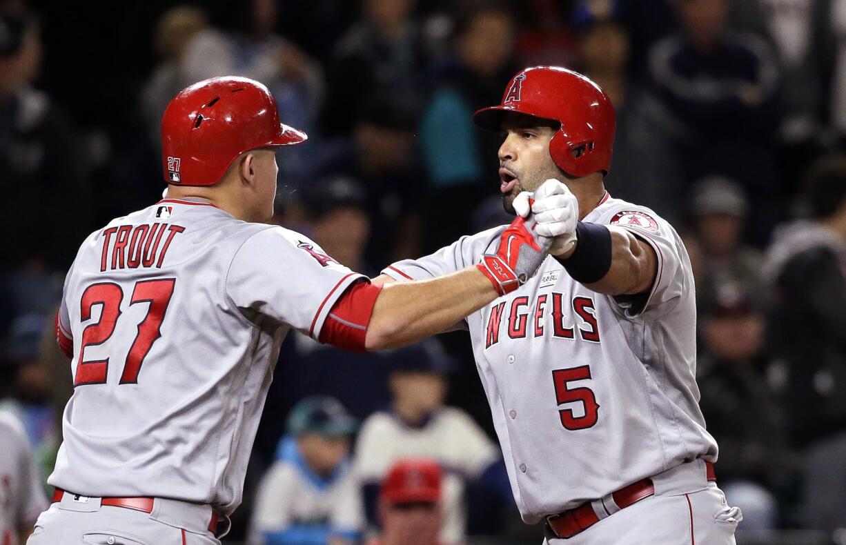 Los Angeles Angels' Albert Pujols (5) is greeted at home by Mike Trout on Pujols' three-run home run against the Seattle Mariners during the ninth inning of a baseball game Saturday, May 14, 2016, in Seattle.