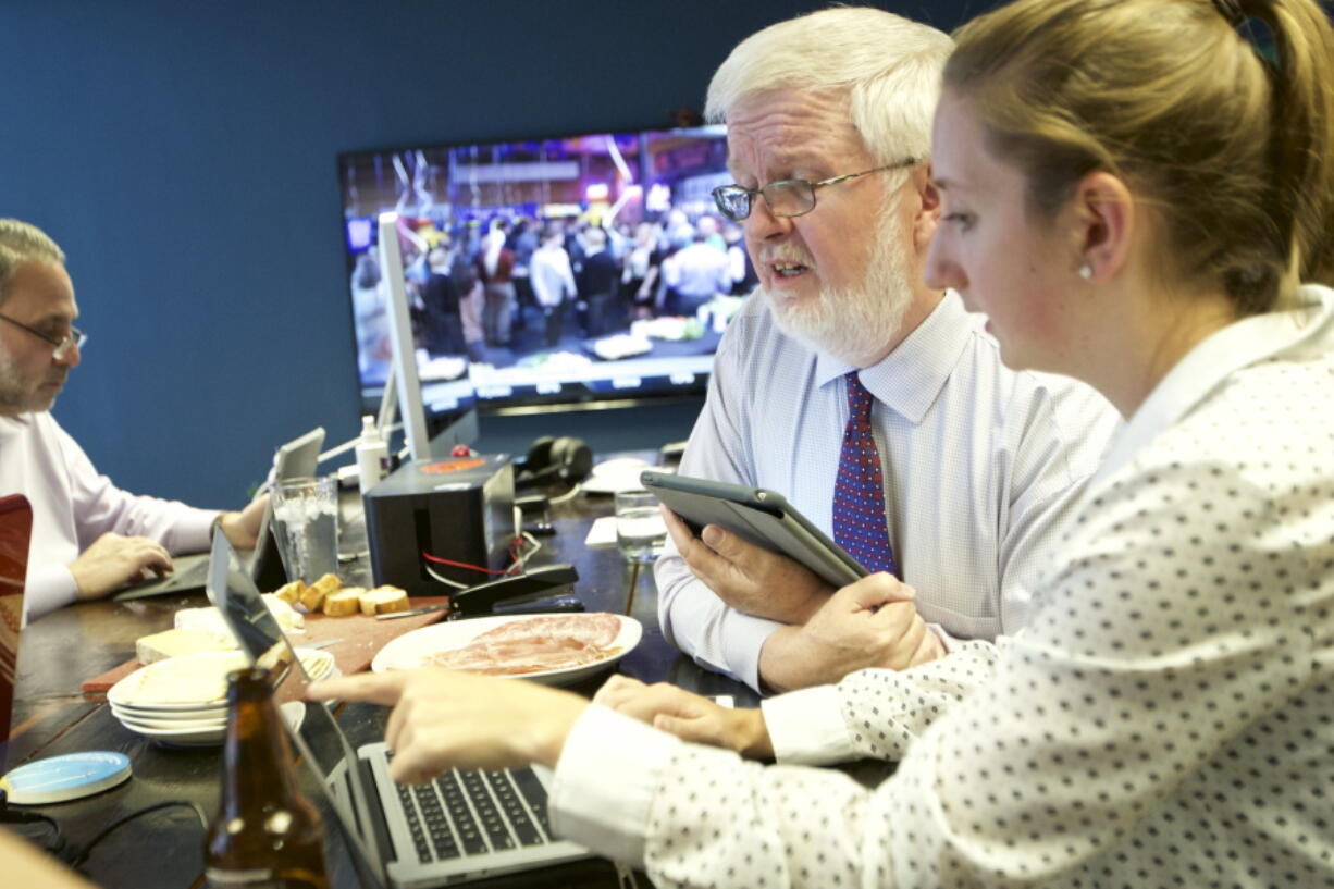 Oregon Democratic Secretary of State candidate Richard Devlin, center, watches returns with his campaign director Emily Brixey, right, in Portland.