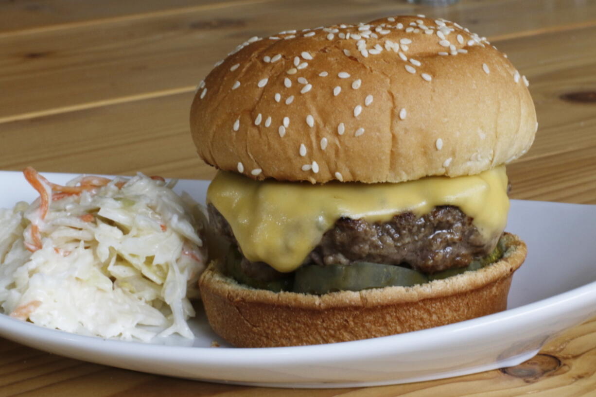 A grilled cheeseburger.  Consider a cast-iron grill platter, a thick, flat sheet of cast iron, to grill up the perfect summer burger.   (AP Photo/J.M.