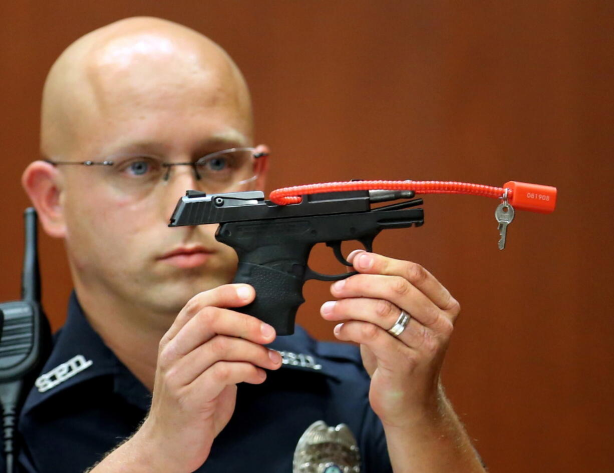 Sanford police officer Timothy Smith holds up the gun that was used to kill Trayvon Martin while testifying in the George Zimmerman trial on  June 28, 2013,  in Sanford, Fla.