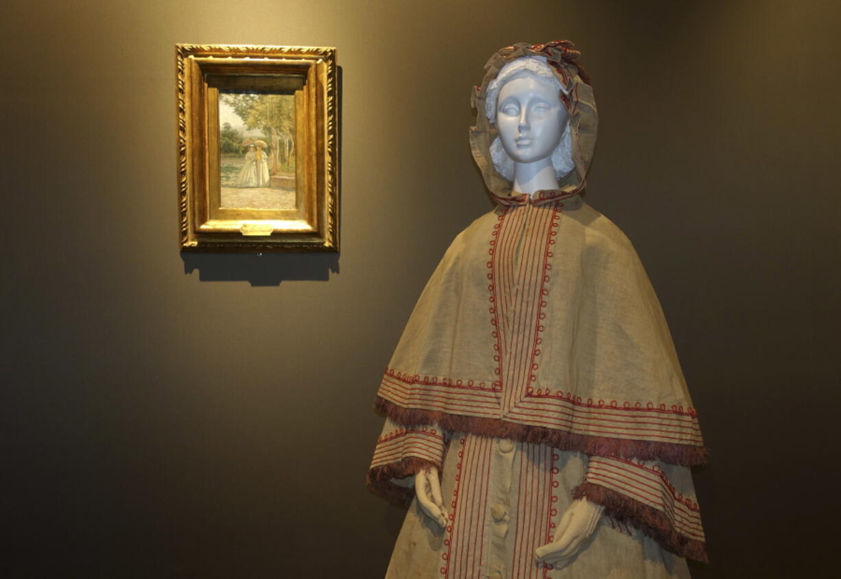 An Italian-made linen garden dress with hooded cape, made in 1865, is shown alongside a 19th Century painting from the Uffizi Gallery&#039;s Galleria di Arte Moderna collection depicting a similar style for a collateral show at Pitti Palace in Florence, Italy, organized as part of the &quot;Across Art and Fashion&#039;&#039; series of exhibits at locations throughout Florence. The exhibit opened Thursday as Italy&#039;s Renaissance capital is reclaiming its centuries-old role as an incubator of the fashion-art dynamic.