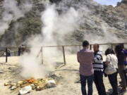 Visitors look at steaming fumarolas at the Solfatara Crater bed, in the Phlegraean Fields near Naples, Italy. In ancient times the site was believed to be the door to hell.