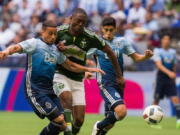 Vancouver Whitecaps' Erik Hurtado, left, fights for the ball against Portland Timbers' Fanendo Adi, center, during the second half of an MLS soccer game in Vancouver, British Columbia, Saturday, May 7, 2016.