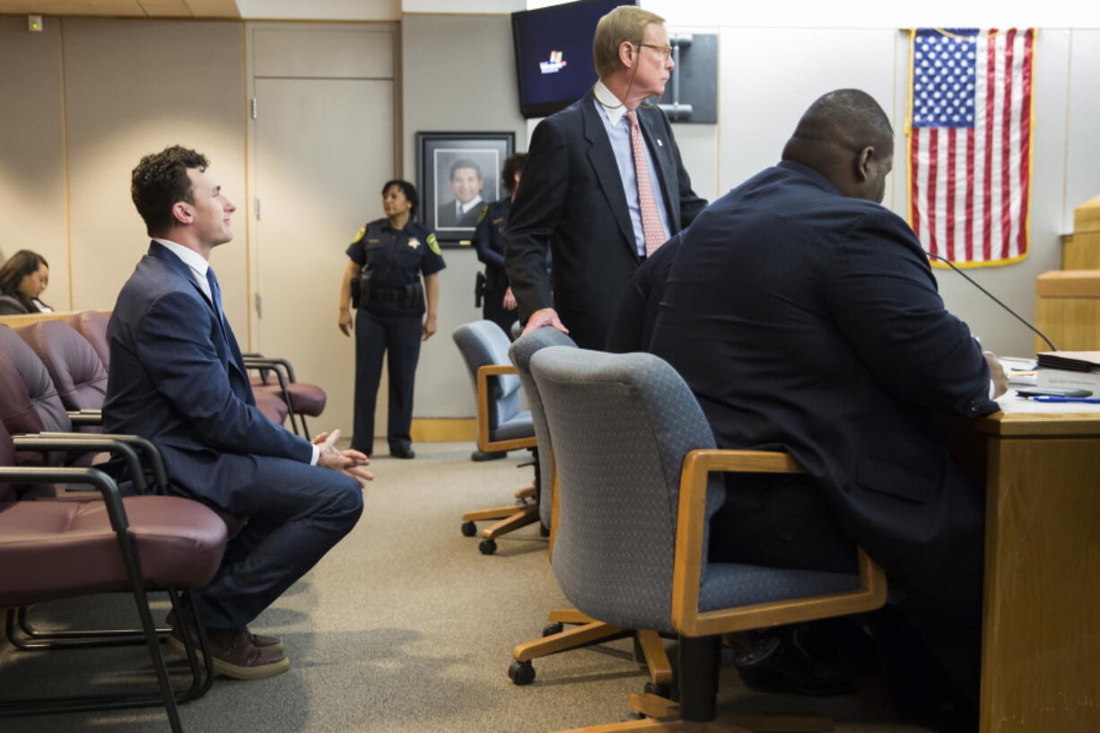 Former Cleveland Browns quarterback Johnny Manziel, left, sits while his defense attorneys confer with the prosecution during his initial hearing Thursday in Dallas. The Heisman Trophy winner and former Texas A&amp;M star was indicted by a grand jury last month after his ex-girlfriend alleged he hit her and threatened to kill her during a night out in January. No plea was entered, but defense attorney Robert Hinton says Manziel plans to plead not guilty. (Smiley N.