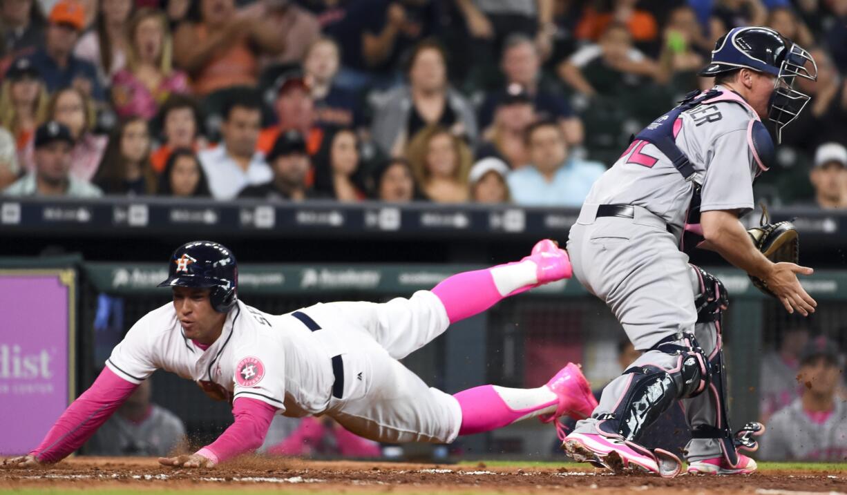 Houston Astros' George Springer, left, slides safely home past Seattle Mariners catcher Steve Clevenger on Carlos Correa's RBI-single in the seventh inning of a baseball game Sunday, May 8, 2016, in Houston.