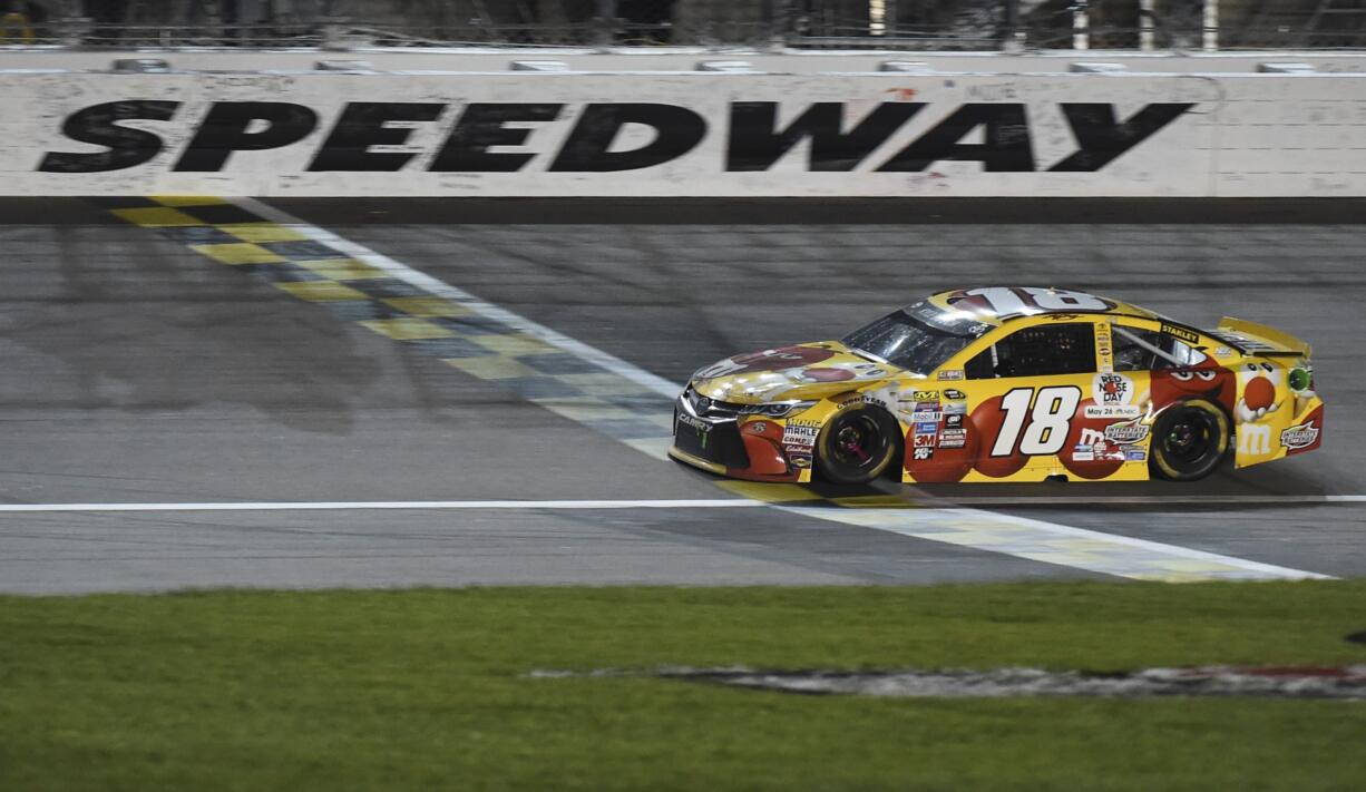 Kyle Busch (18) crosses the finish line to win a NASCAR Sprint Cup Series race at Kansas Speedway in Kansas City, Kan., Saturday, May 7, 2016.