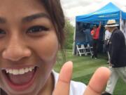 Julieta Rendon-Mendoza of Union High School poses for a selfie with Tiger Woods (in red) in the background at the Junior Invitational at Sage Valley Golf Course in South Carolina.