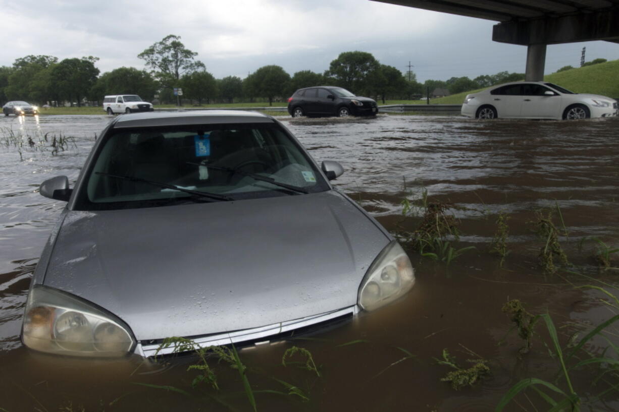 Vehicles slowly drive past a flooded car near an exit ramp on Interstate 49 in Grand Coteau, La., as flash floods swept through the area Sunday.