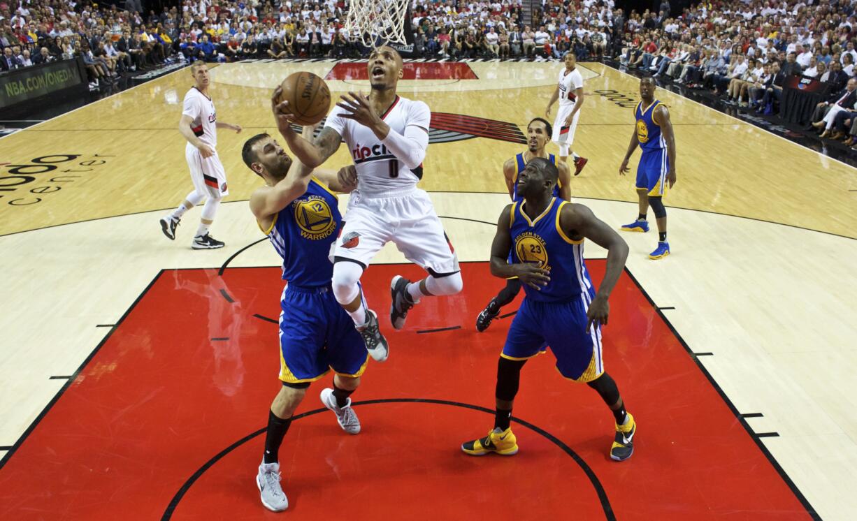 Portland Trail Blazers guard Damian Lillard, center, shoots over Golden State Warriors center Andrew Bogut, left, and forward Draymond Green, right, during the first half of Game 3 of an NBA basketball second-round playoff series Saturday, May 7, 2016, in Portland, Ore.