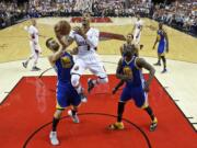 Portland Trail Blazers guard Damian Lillard, center, shoots over Golden State Warriors center Andrew Bogut, left, and forward Draymond Green, right, during the first half of Game 3 of an NBA basketball second-round playoff series Saturday, May 7, 2016, in Portland, Ore.