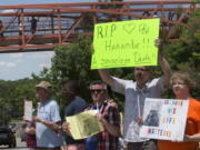 Zoo visitors look at protesters and mourners from a pedestrian bridge Monday during a vigil for the gorilla Harambe outside the Cincinnati Zoo &amp; Botanical Garden in Cincinnati. Harambe was killed Saturday at the Cincinnati Zoo after a 4-year-old boy slipped into an exhibit and a zoo response team concluded the boy&#039;s life was in danger.