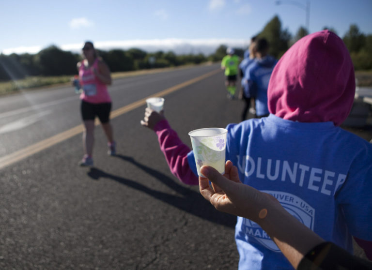 Volunteers offer water to runners taking part in the Vancouver Marathon, near Vancouver Lake Sunday June 19 2016.