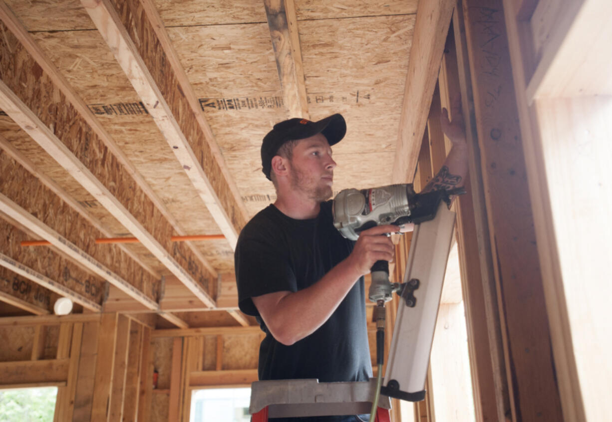 Robby Wilson works with a nail gun on May 16 at a construction site of a new apartment complex in downtown Vancouver.