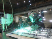 Gary Baker welds a section of a plaque at Vancouver Bolt and Supply that will be part of a Vietnam memorial.