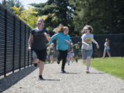 Fifth-graders Sara Watson, from left, Taylor Allsup and Kaylen Duncan keep pace as they jog laps around Hockinson Heights Elementary School&#039;s new track last week. Donations from community members and from Karvonen Sand and Gravel made the newly remodeled track possible.