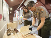 Meagan Huff, left, and curator Theresa Langford look through a log book for an appropriate page to display in the new Pearson Air Museum exhibit highlighting the 1937 Chkalov flight.